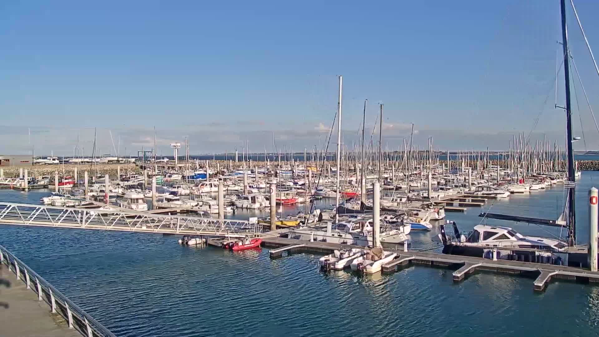 A large marina filled with numerous sailboats and motorboats on a sunny day.
