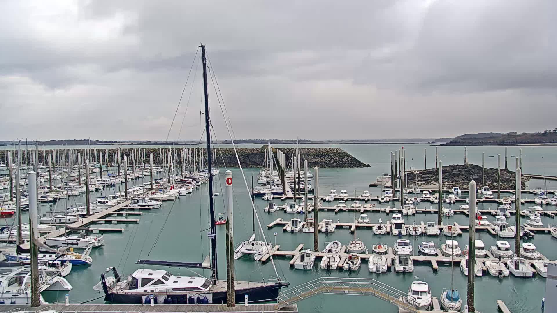 A marina filled with numerous sailboats and motorboats under a cloudy sky.