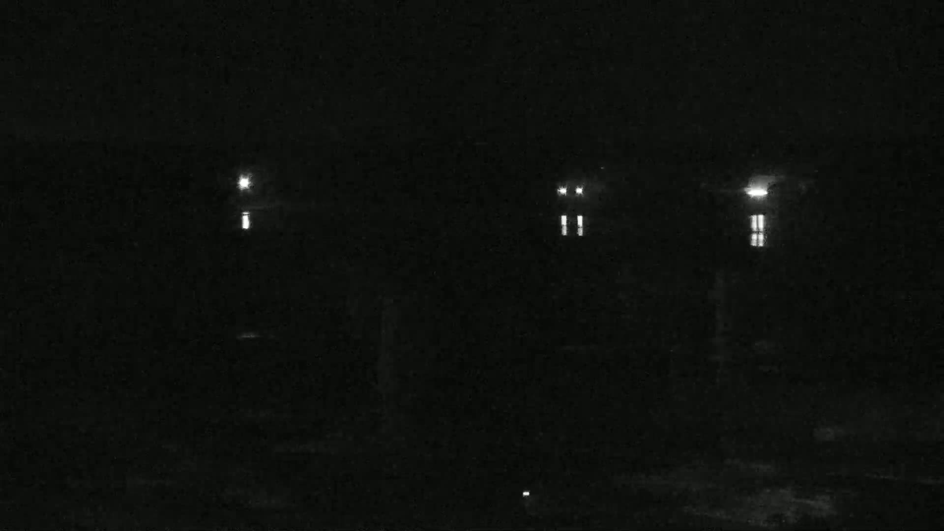 At night, several illuminated windows are visible on a dark building.