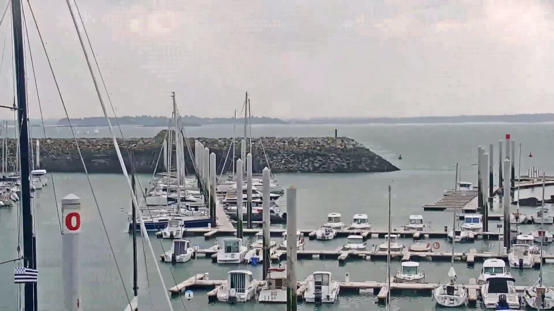 A marina filled with numerous boats and yachts is seen on an overcast day.