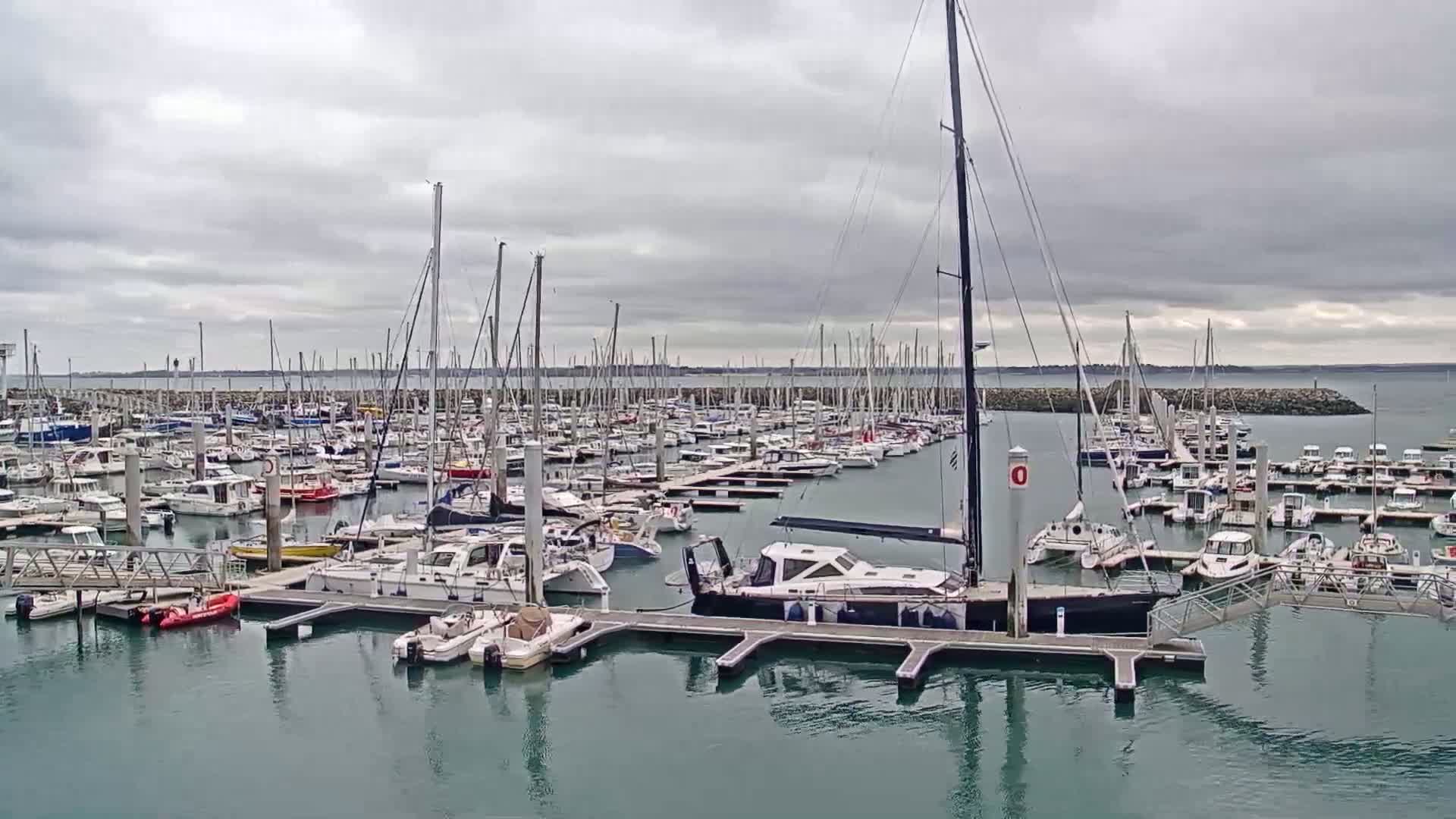 A marina filled with numerous sailboats and motorboats under an overcast sky.
