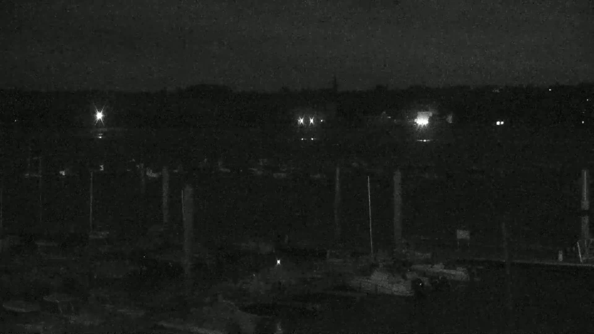 A nighttime, low-light view of a marina with numerous boats moored at their slips.