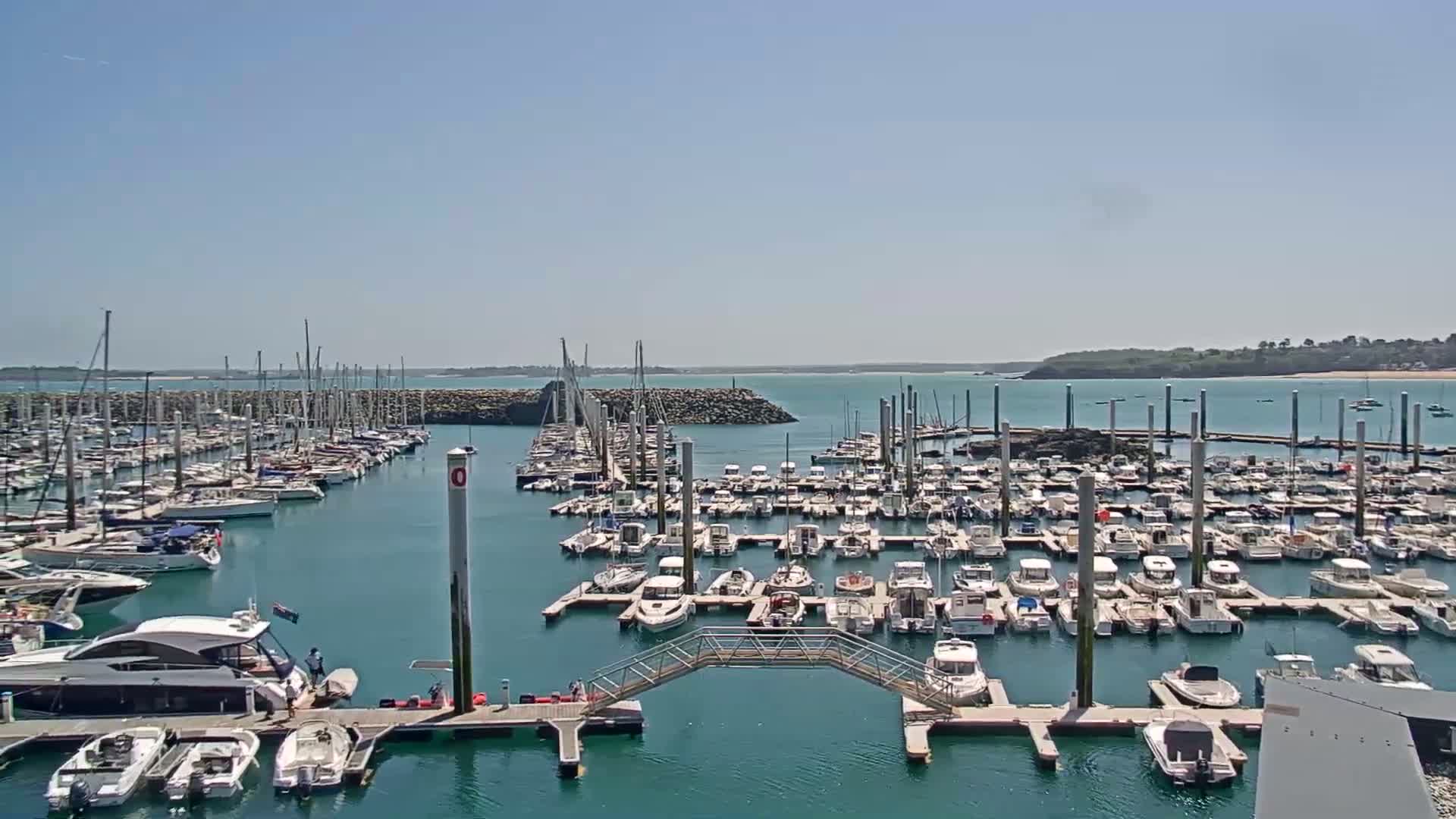 A marina filled with numerous boats and yachts is seen on a sunny day.