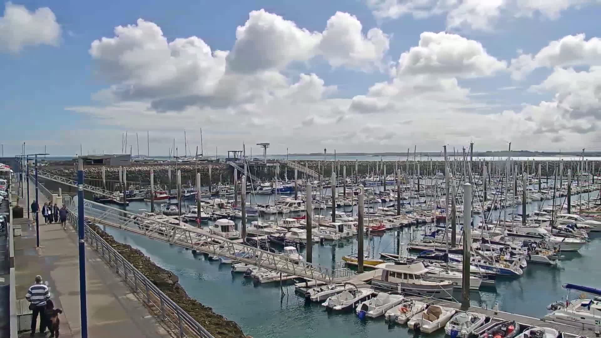 A marina filled with numerous boats and yachts under a partly cloudy sky.