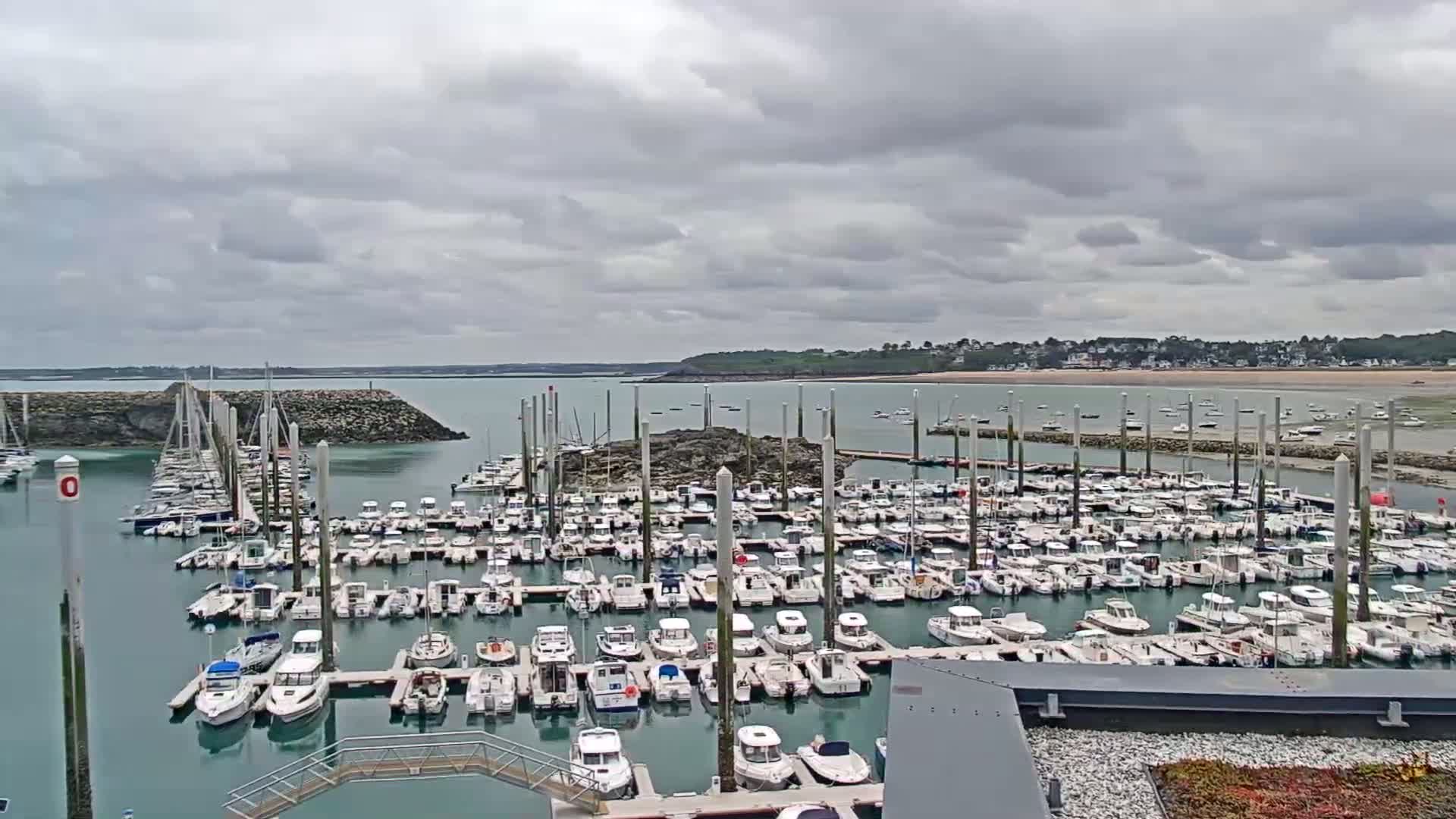 A large marina filled with numerous boats is shown under an overcast sky.