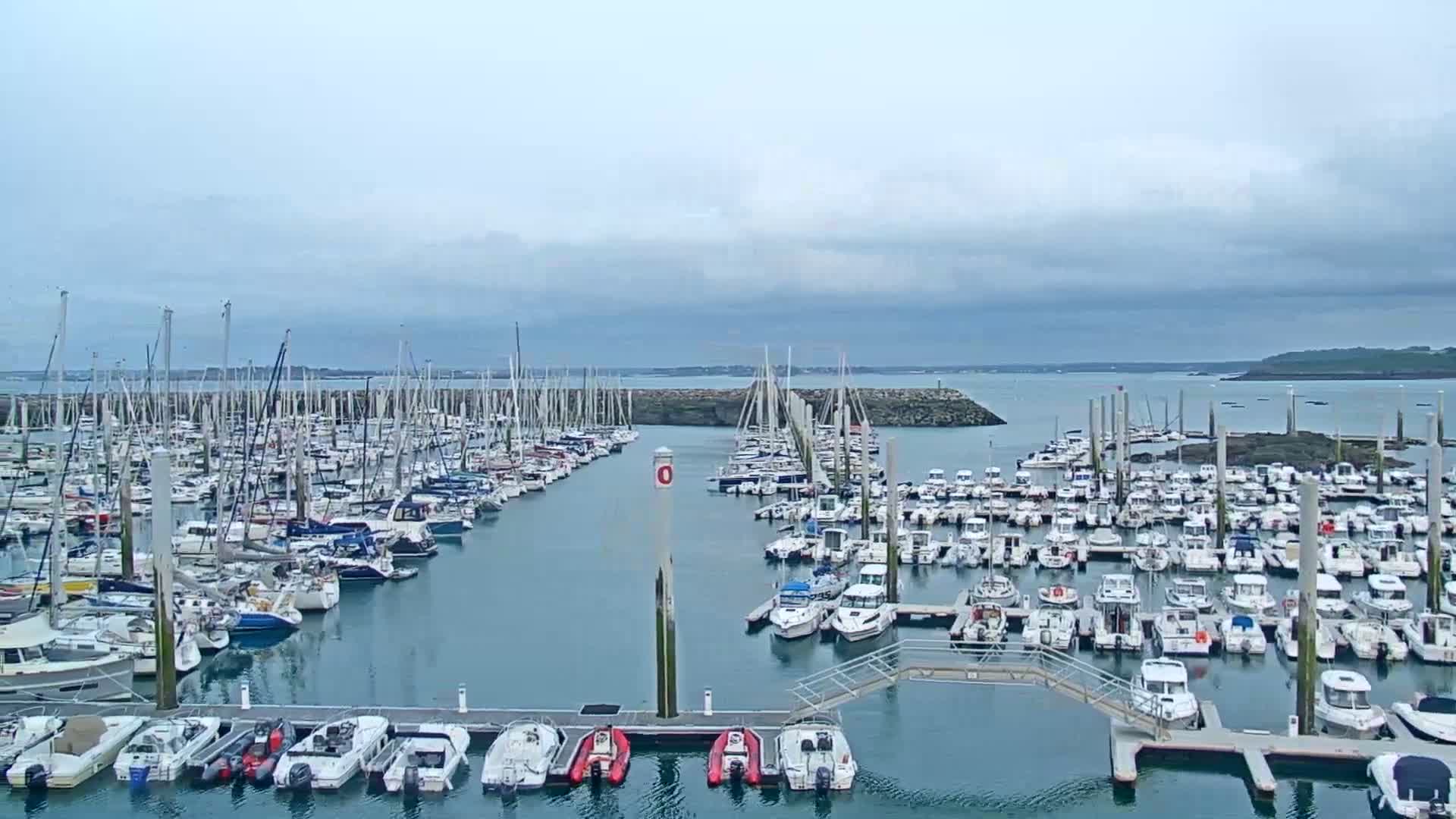 A large marina filled with numerous sailboats and motorboats under a cloudy sky.