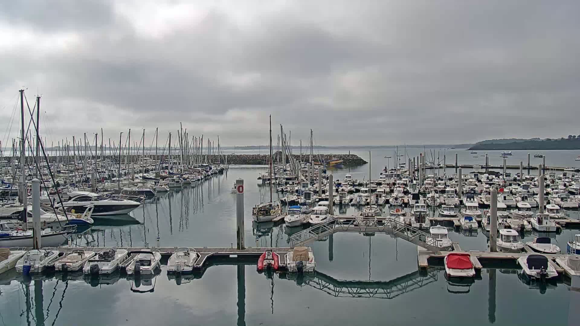 A large marina filled with many sailboats and motorboats is shown on an overcast day.