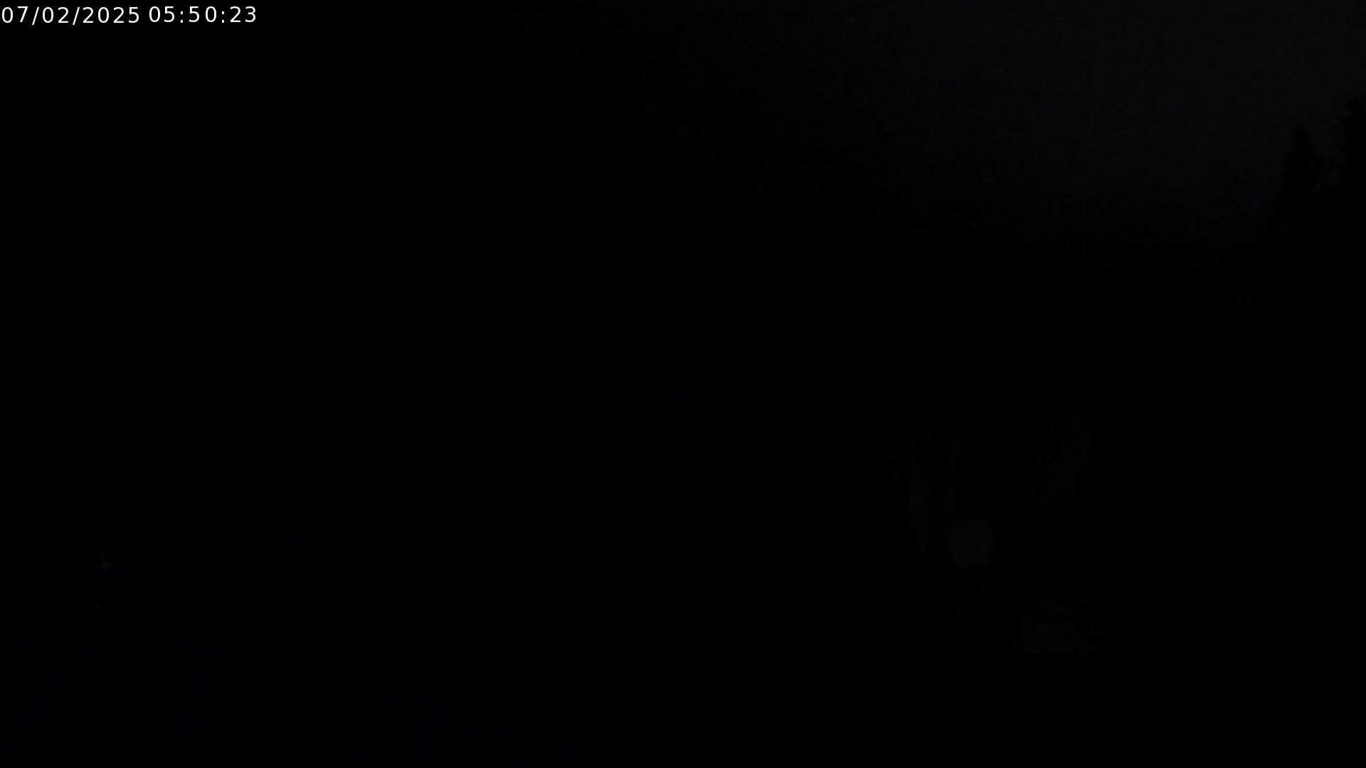 A very dark, nighttime image shows a mostly black scene with a few faint, indiscernible shapes in the lower right.