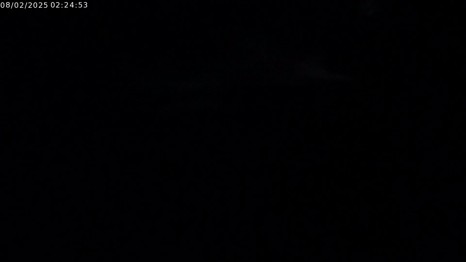 The image is almost entirely black, with a faint suggestion of a light, cloudy sky visible at the top.