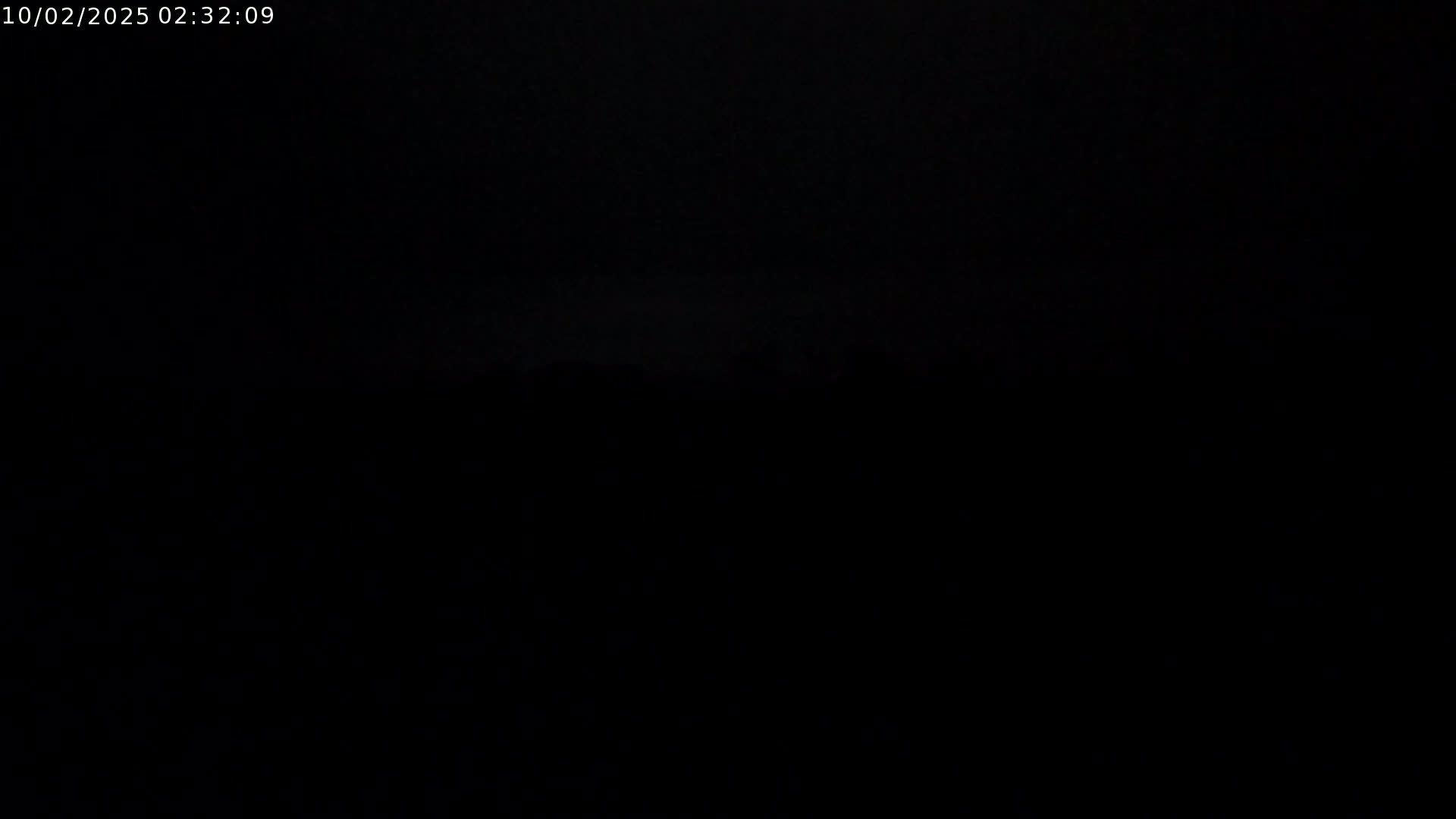 A dark, nighttime outdoor scene shows a barely visible, indistinct horizon line.