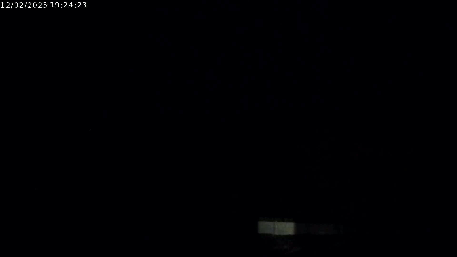 A very dark nighttime scene shows a faint, horizontally oriented, light gray object at the bottom.