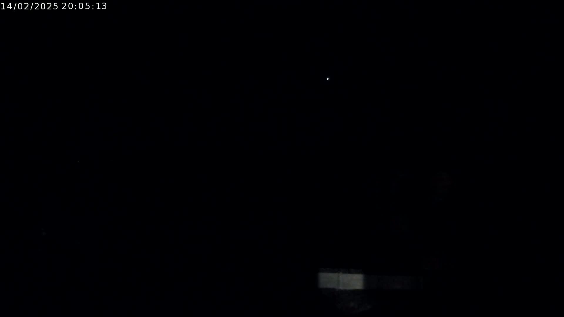 A nighttime outdoor scene shows a single bright light in a dark sky, with a faint horizontal light source near the bottom.