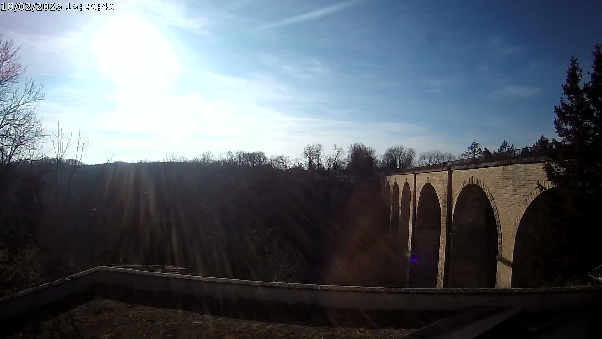A brick viaduct stretches across a valley under a bright, sunny sky.