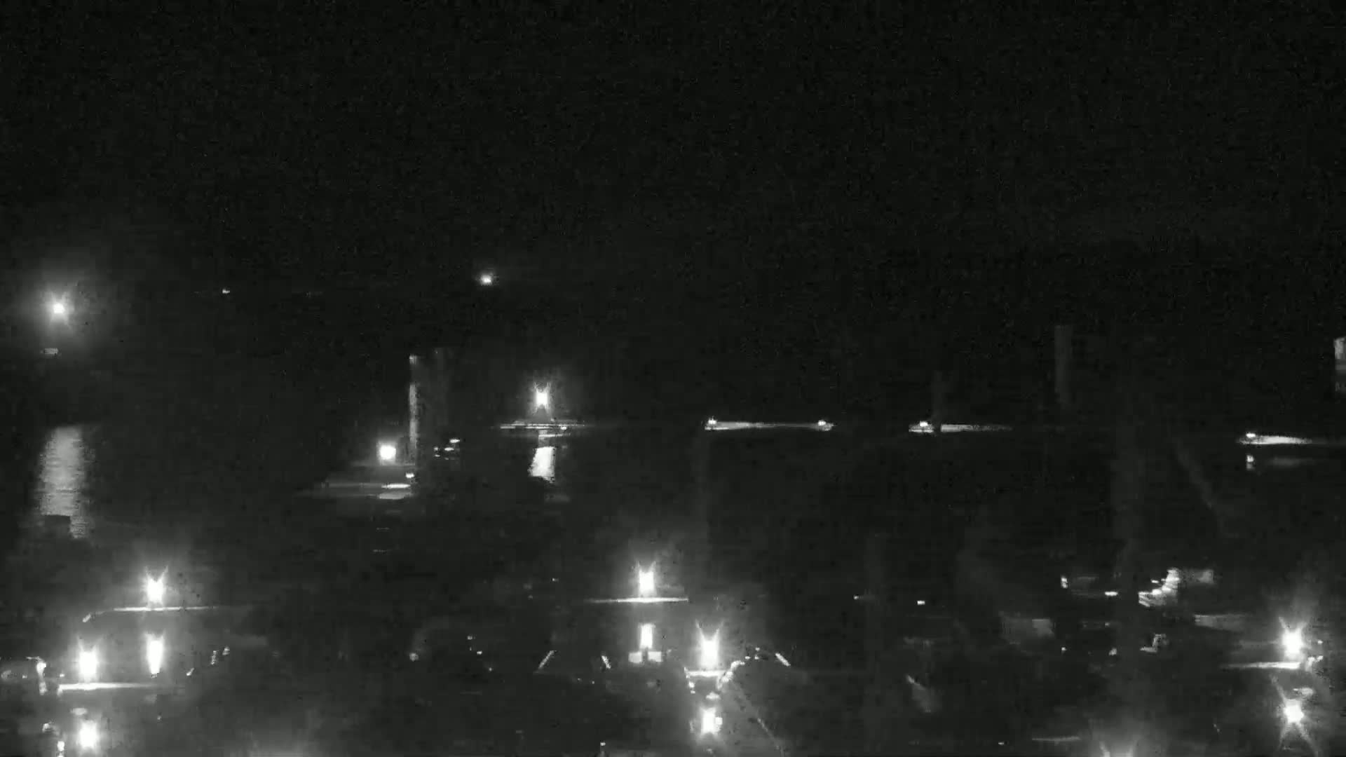 A nighttime, low-light view of a body of water with numerous lights visible on the far shore and in the water itself.