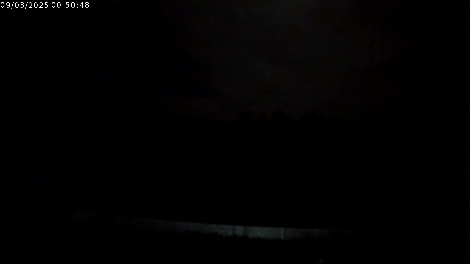 A dark, nighttime scene shows a low horizon line with a faintly illuminated area at the bottom.