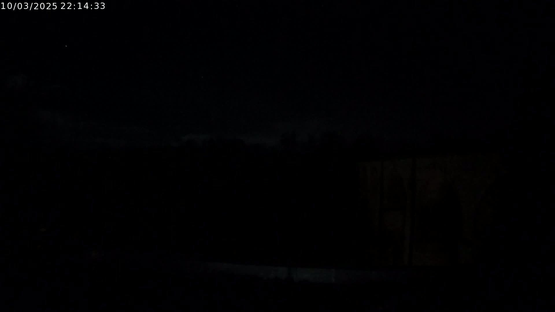 A dark, nighttime scene shows a mostly obscured landscape under a cloudy sky.