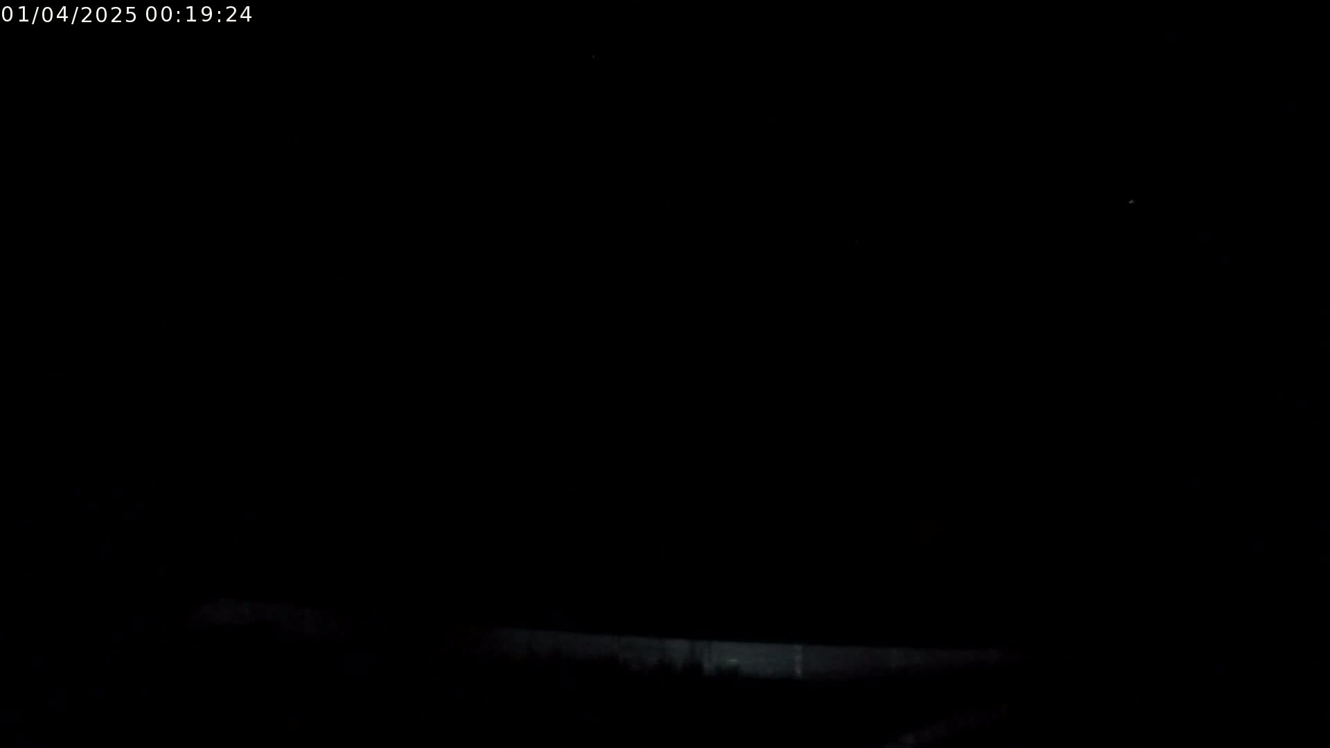 A dark nighttime scene shows a low horizontal line, possibly a fence or wall, separating the bottom of the frame from a completely black sky.