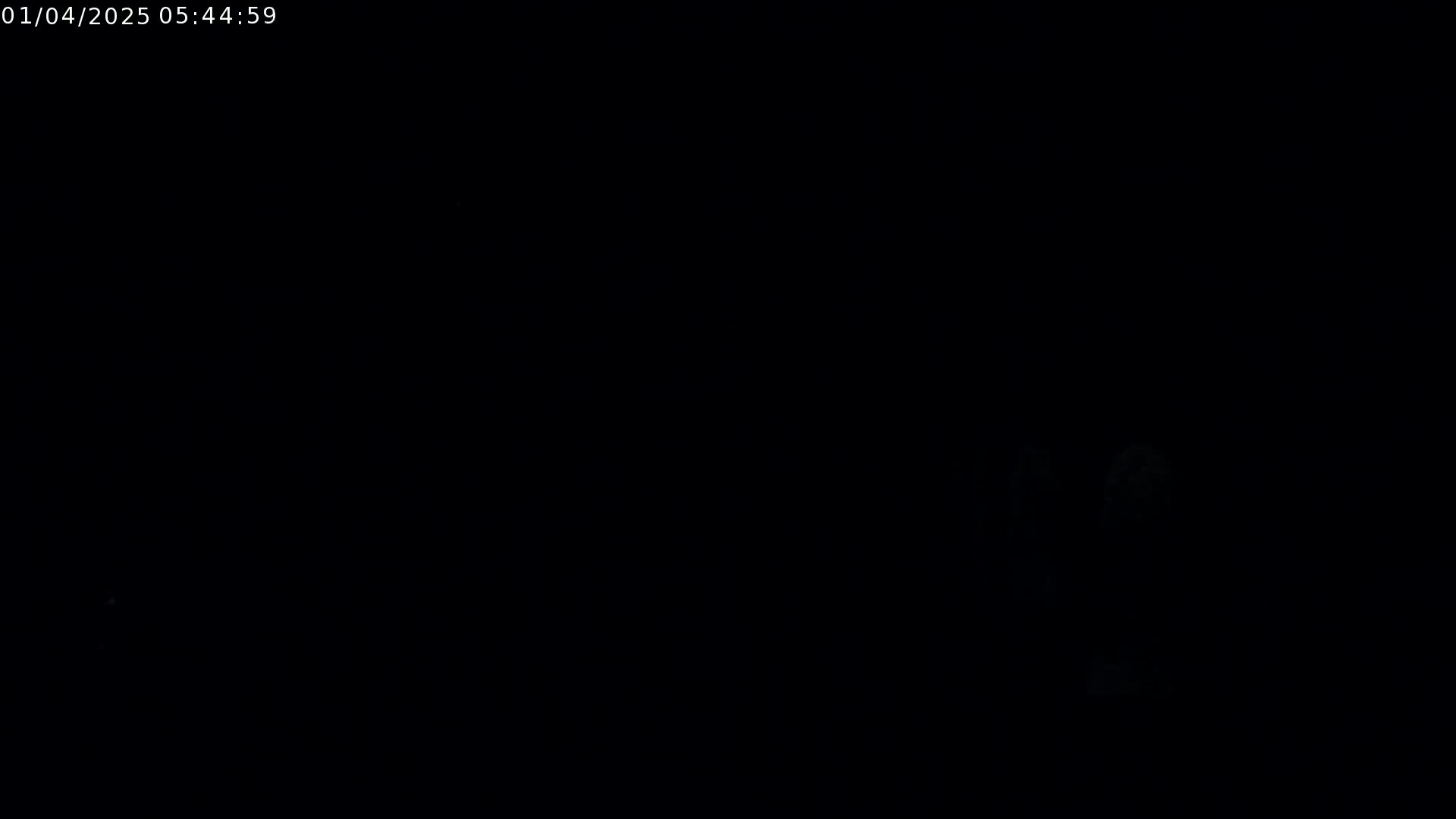 The image is almost entirely black, with a few faint, indistinct light sources visible in the lower right corner.