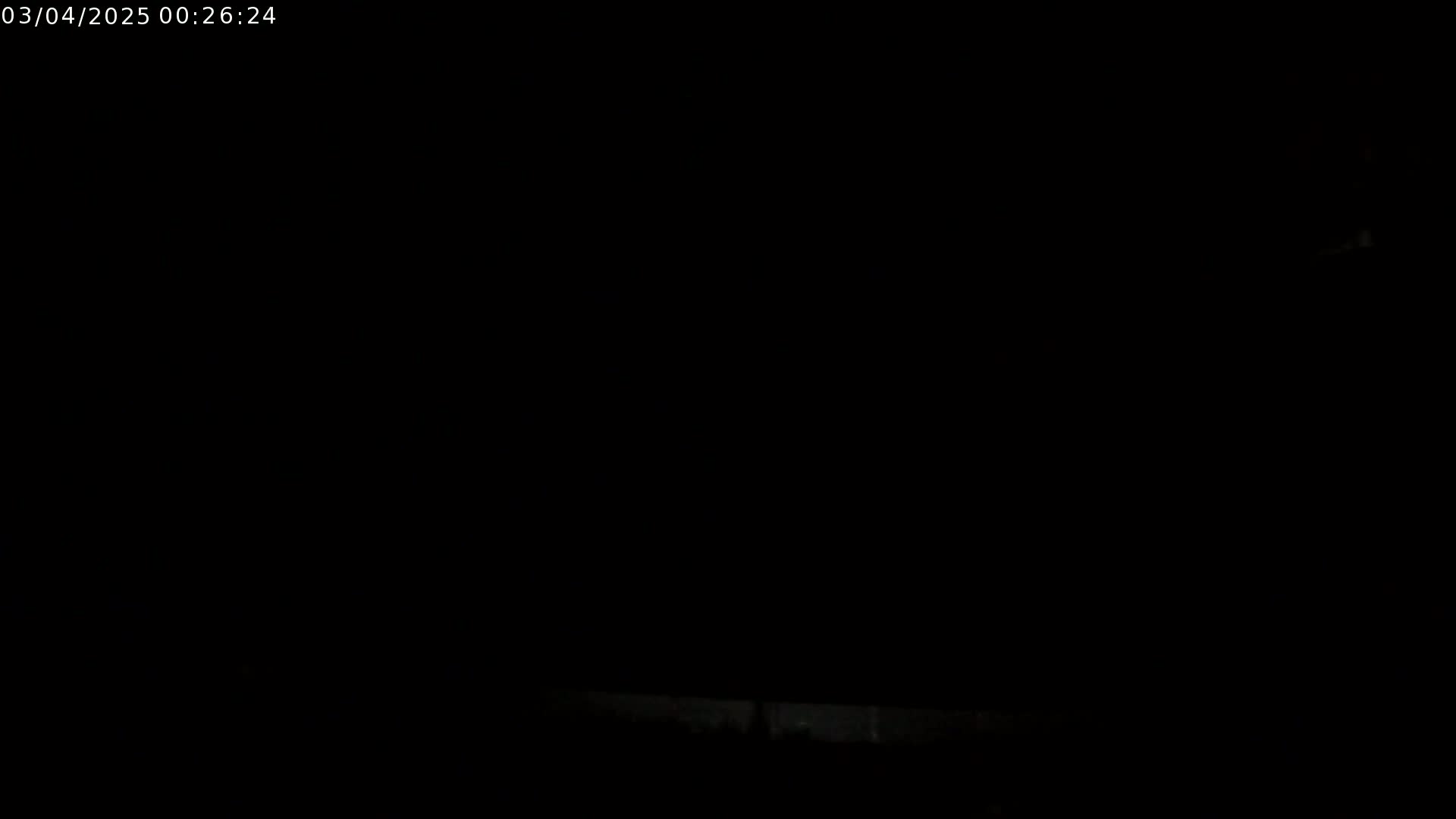 A very dark image shows a faint, barely visible light source near the bottom and a completely dark sky above.