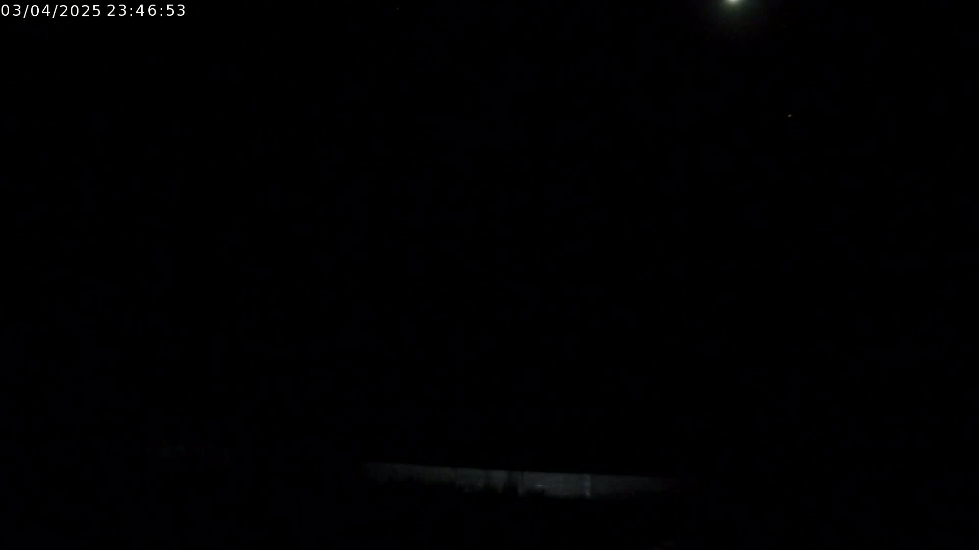 A nighttime outdoor scene shows a bright moon and a dark sky above a low wall or barrier.