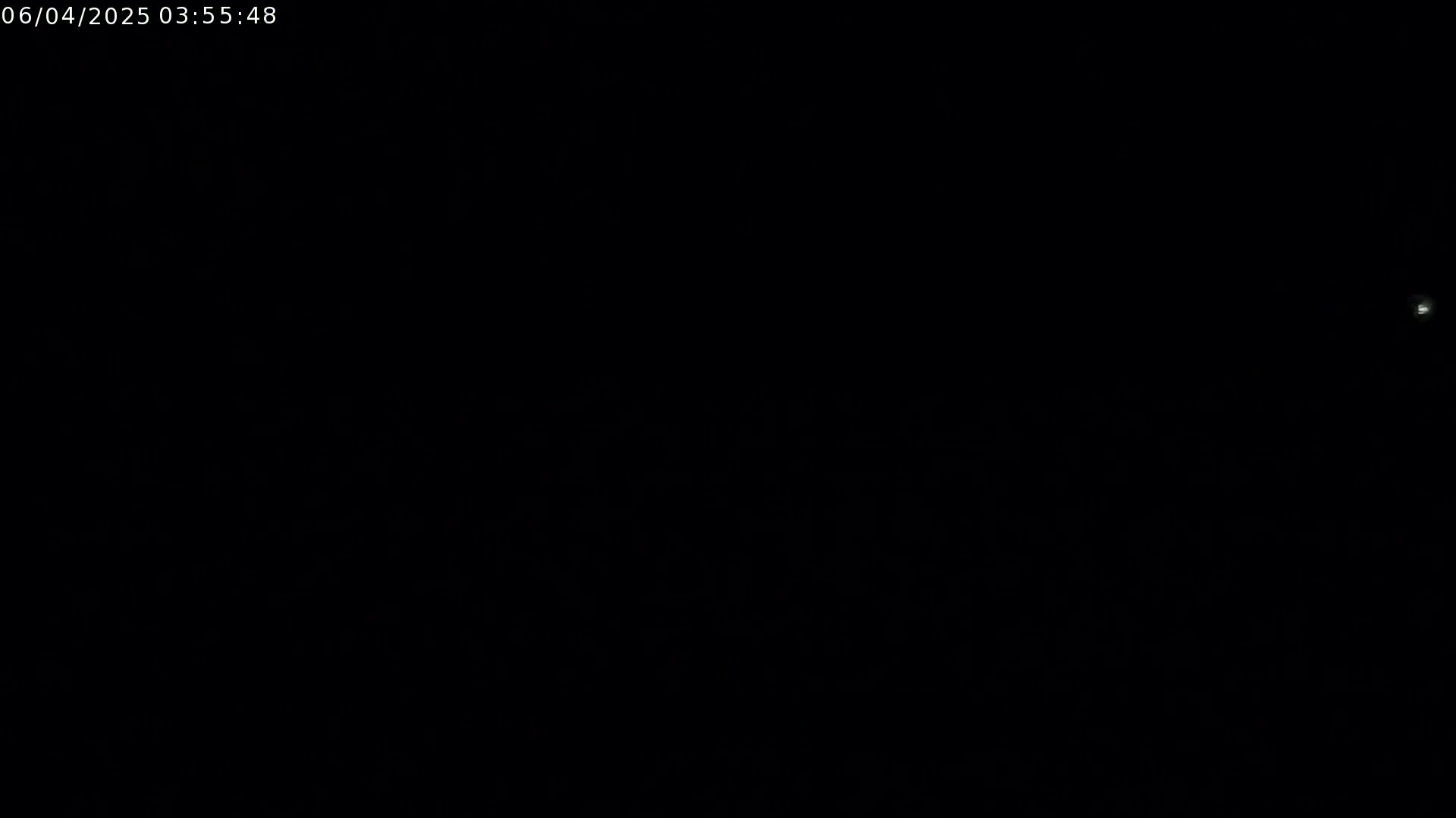 A nearly entirely black image shows a small, faint light source in the upper right corner under nighttime conditions.