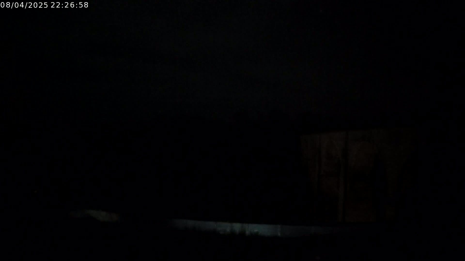 A dark, nighttime scene shows a dimly lit wall and ground.