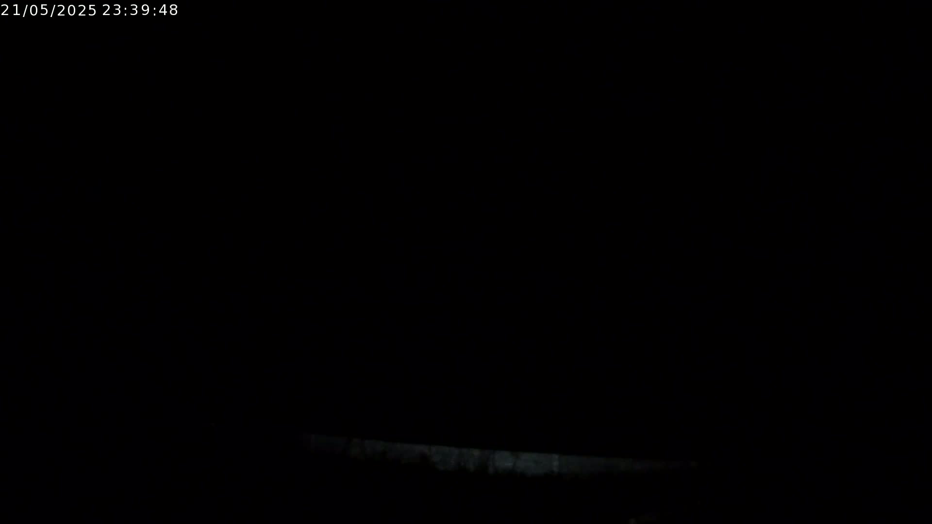 The image shows a very dark scene at night, with a faint, barely visible light source at the bottom.