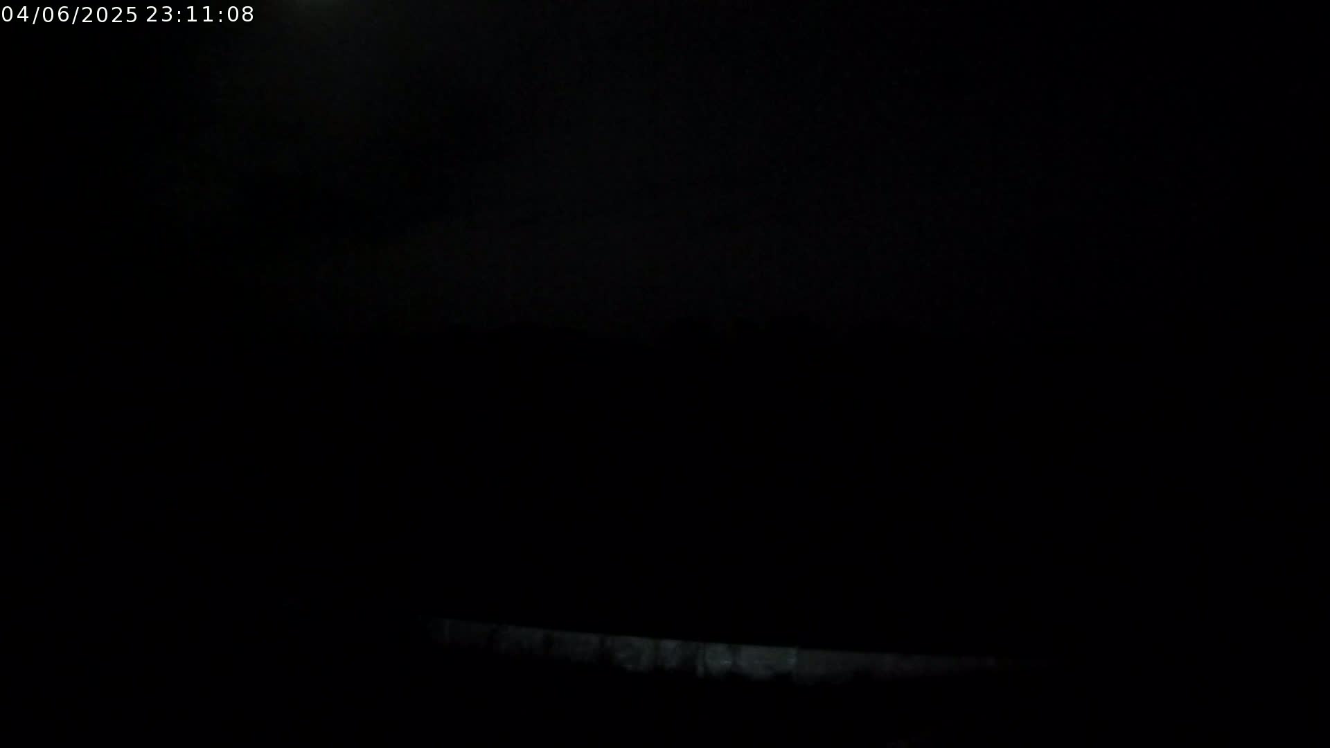 A very dark, possibly nighttime image shows a dimly lit horizontal line at the bottom, suggesting a low-lying object or ground level.