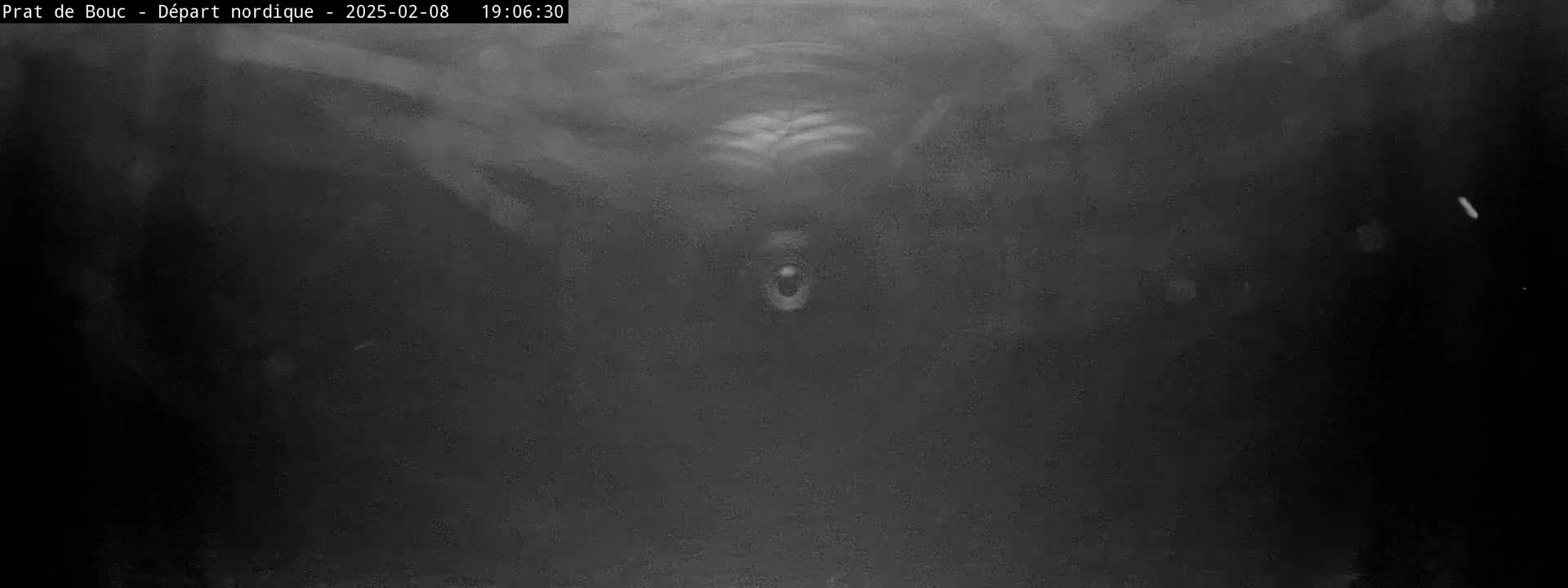 A dark, grainy image shows a mostly black scene with indistinct shapes and some lighter areas suggesting a night-time view.