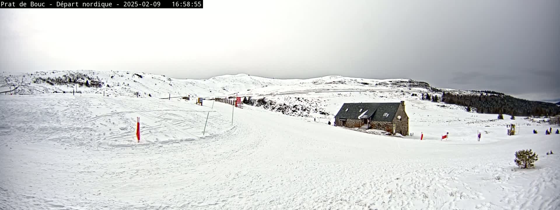 A snow-covered landscape with a stone building, sparsely populated by people, under an overcast sky.