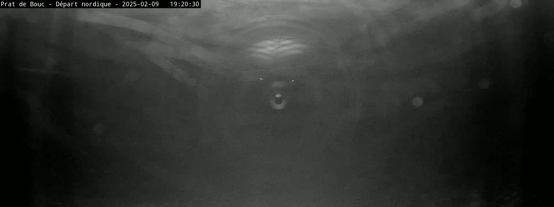 A blurry, dark grayscale image shows a dimly lit tunnel-like space with indistinct shapes in the distance.