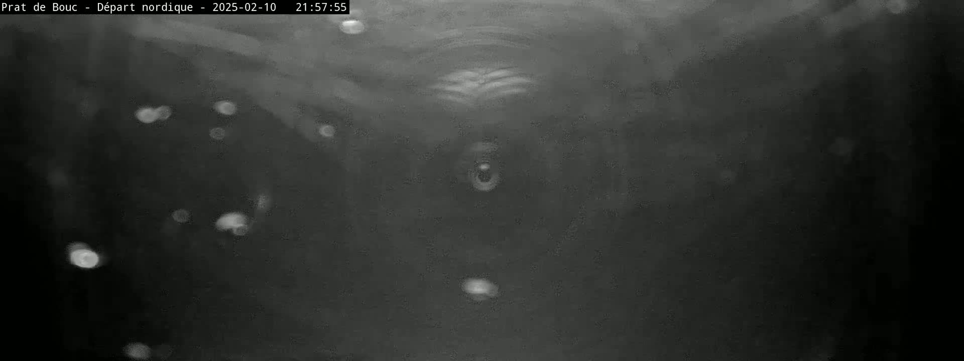 A blurry, dark grayscale image shows a tunnel-like structure with indistinct shapes and light particles floating in the air.