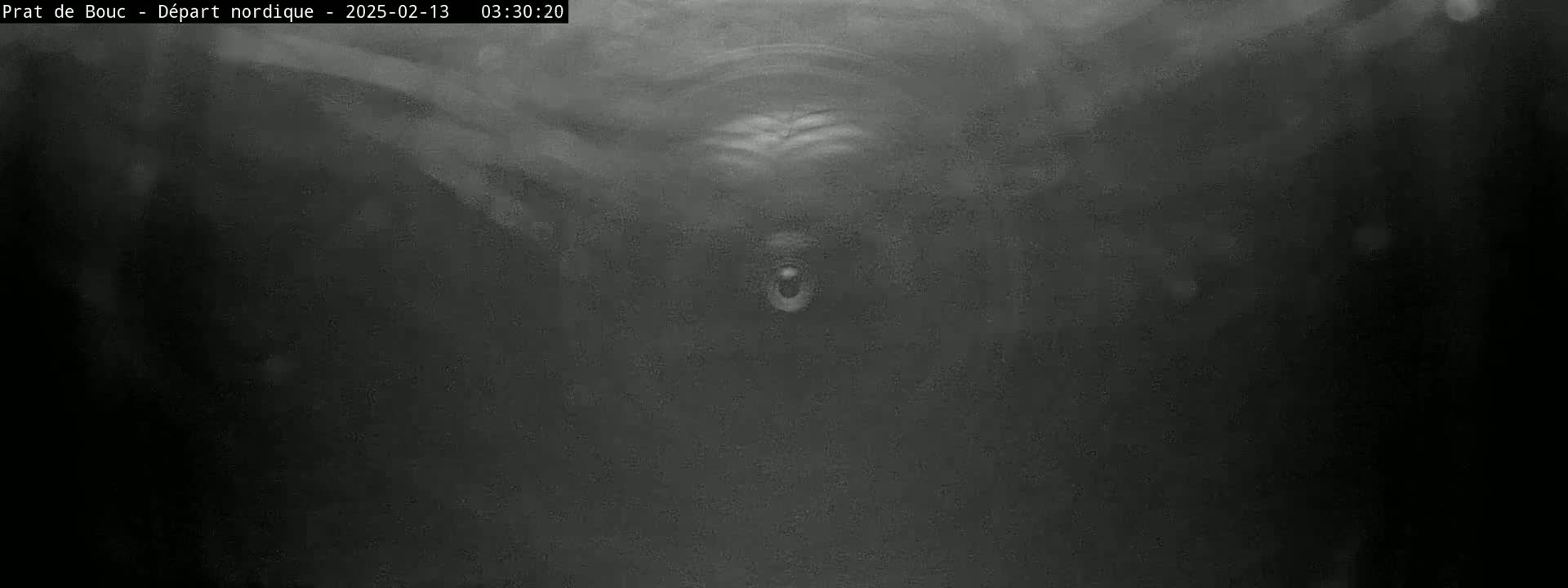 A grainy, low-light image shows a dark, possibly underwater, scene with a small, bright object in the center.
