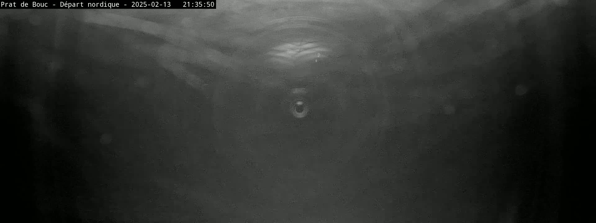 A blurry, dark grayscale image shows a dimly lit space with indistinct shapes and a possible opening in the center.