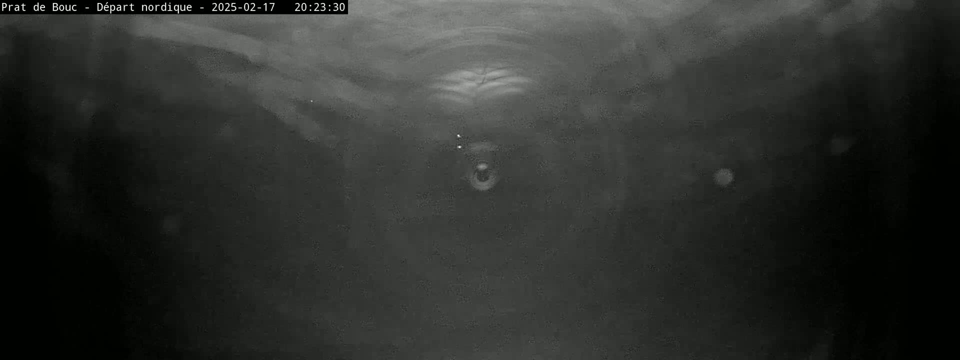 A low-light, grainy image shows a dark, possibly snowy or foggy, environment with a blurry, indistinct object in the center.