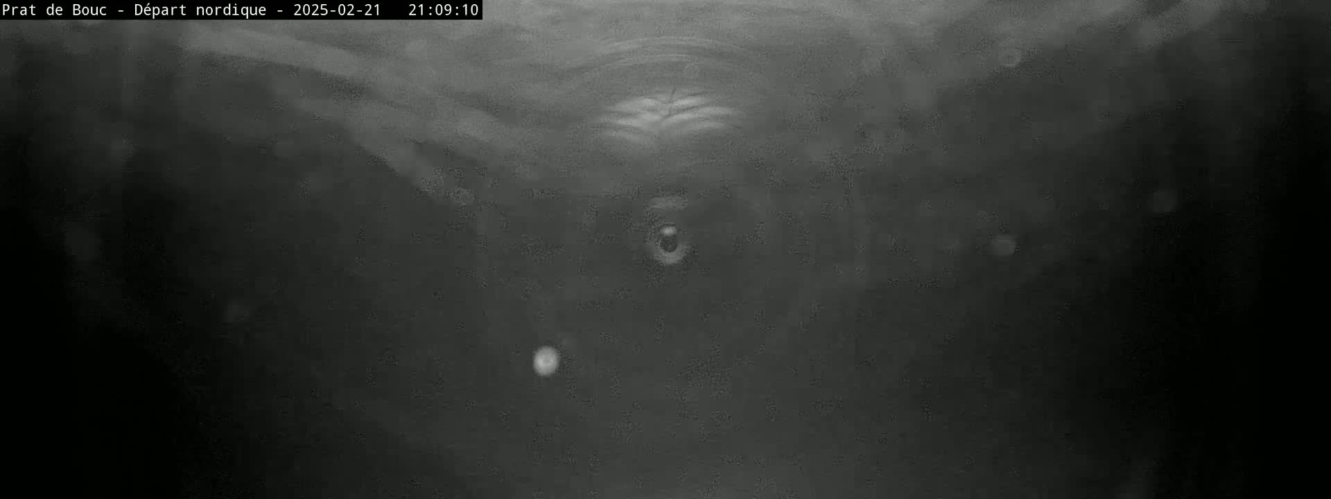 A dark, blurry image shows a dimly lit, possibly underground, space with a few faint, bright spots visible.