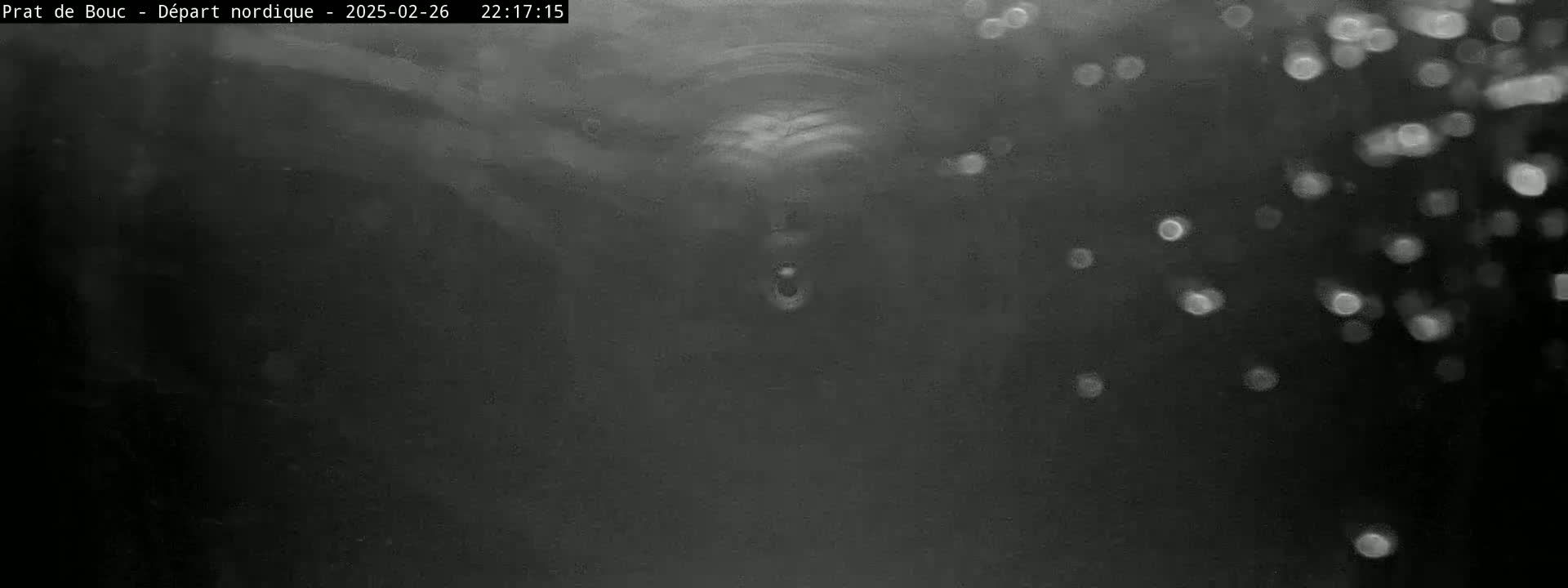 A blurry, dark grayscale image shows what appears to be snow falling in front of a dark tunnel or enclosed space.