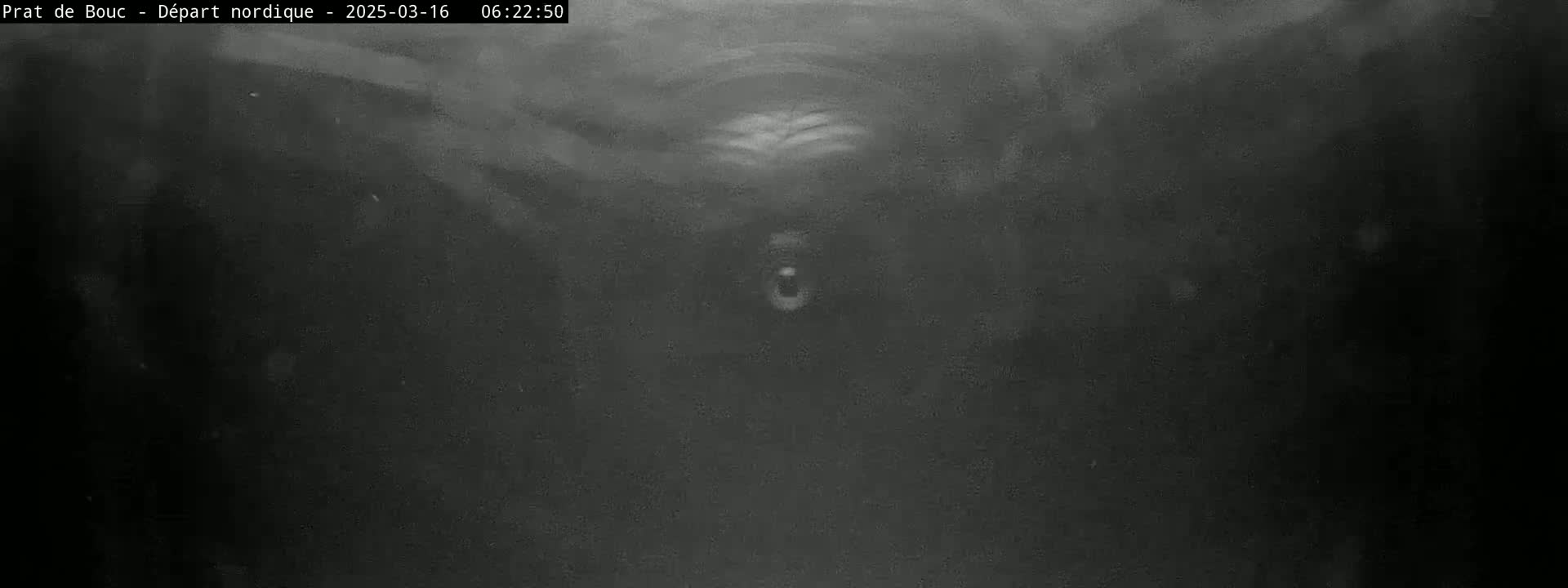 A blurry, low-light grayscale image shows a dark, possibly enclosed, space with faint, hazy details.