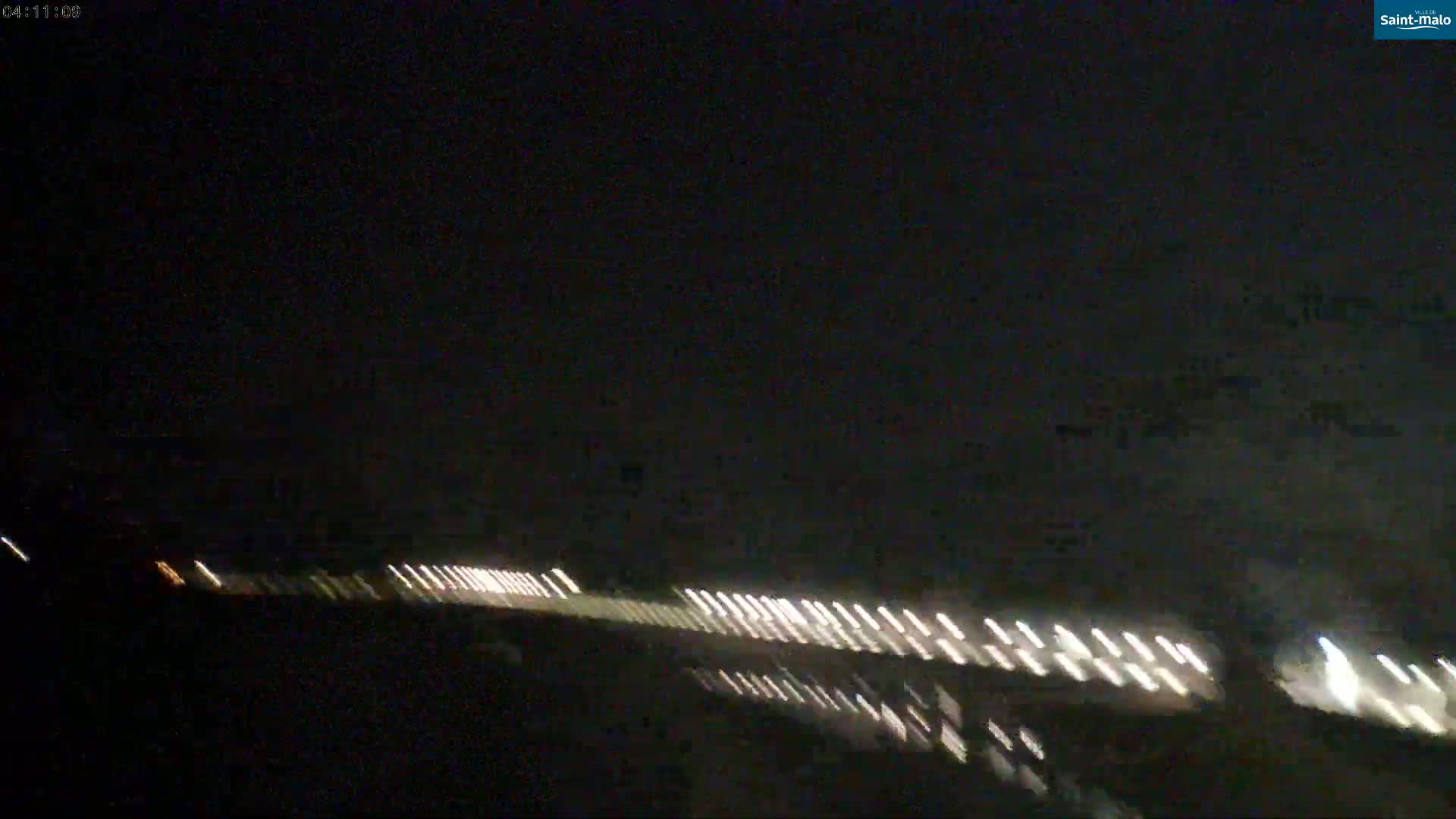 A long line of headlights from vehicles is visible at night.