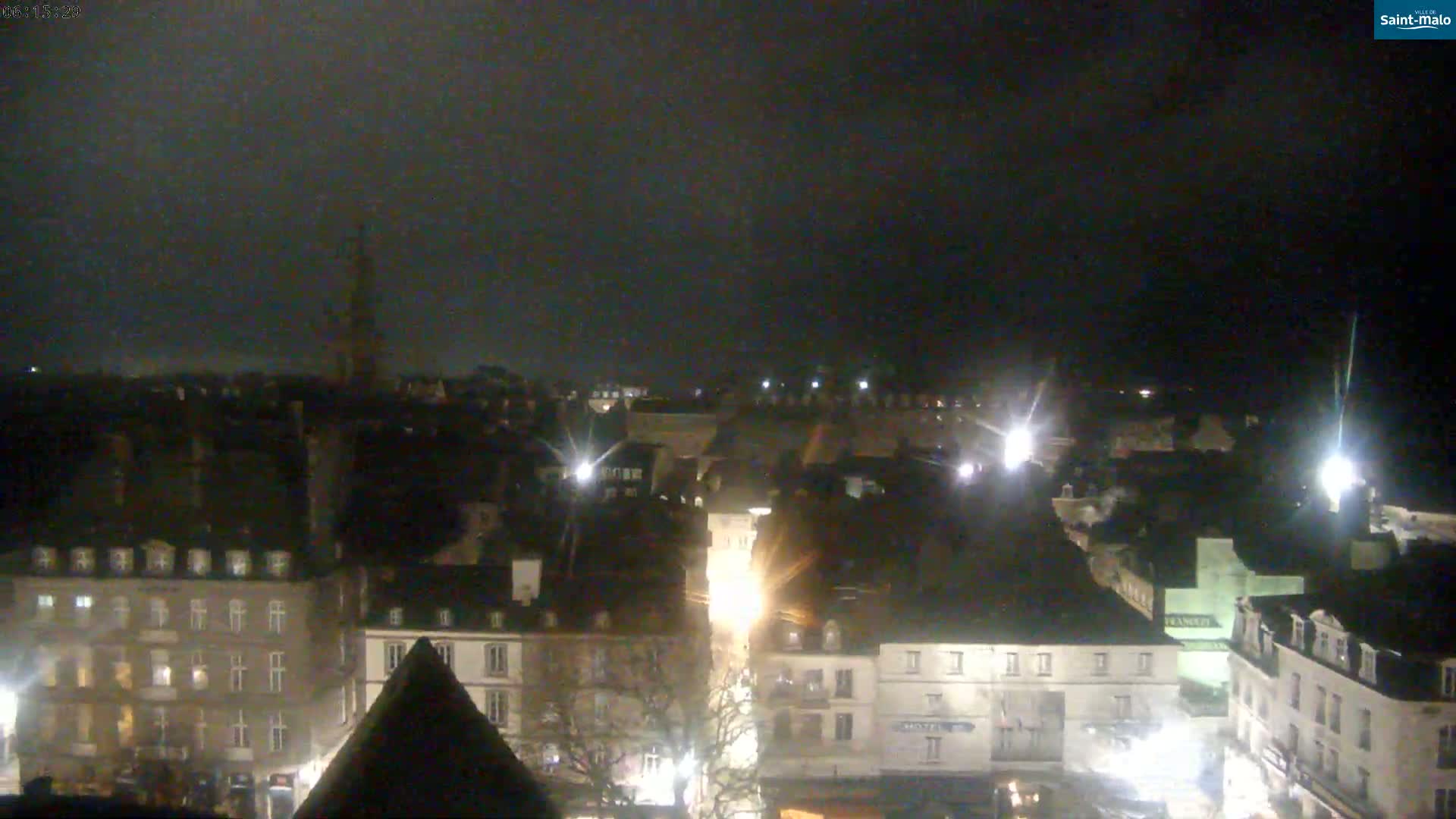 A nighttime aerial view of a city with dark skies and illuminated buildings.
