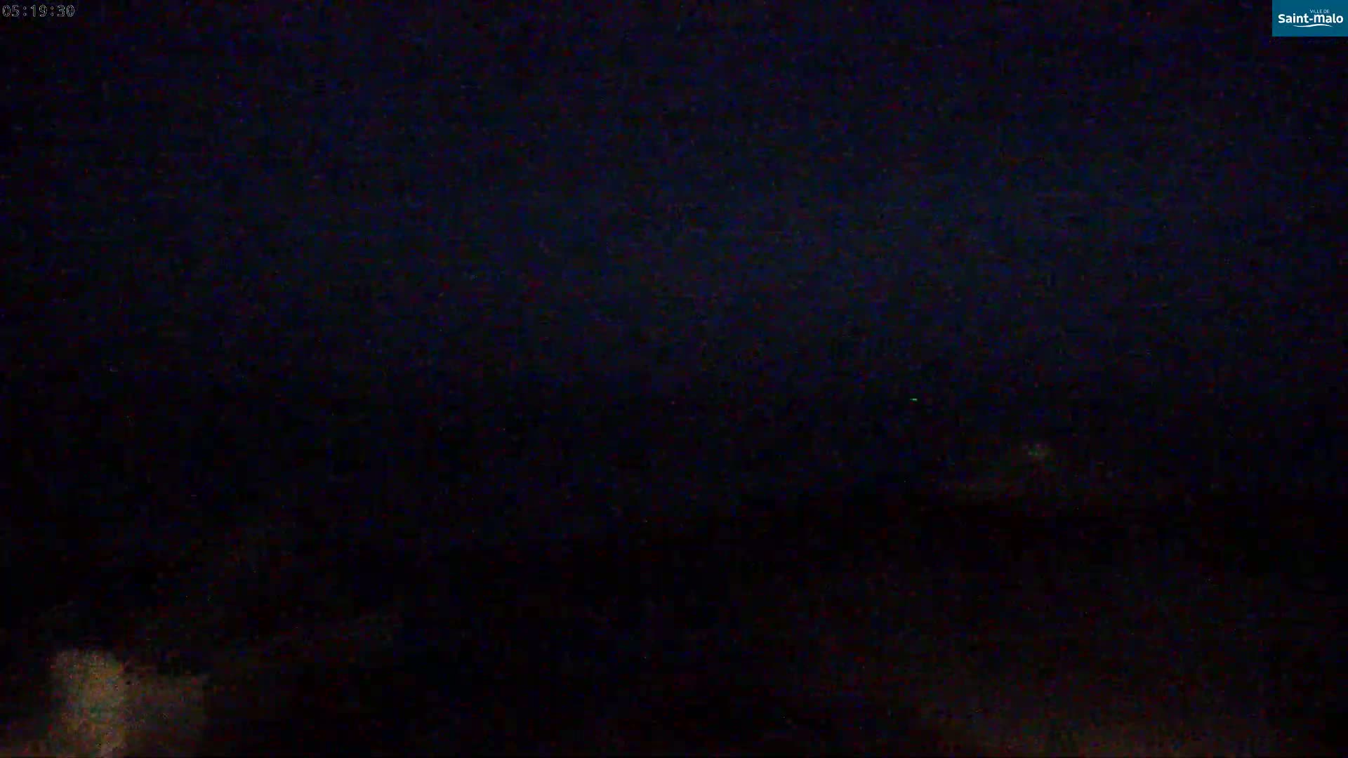 A dark, nighttime scene shows a blurry, indistinct landscape under a mostly clear sky.