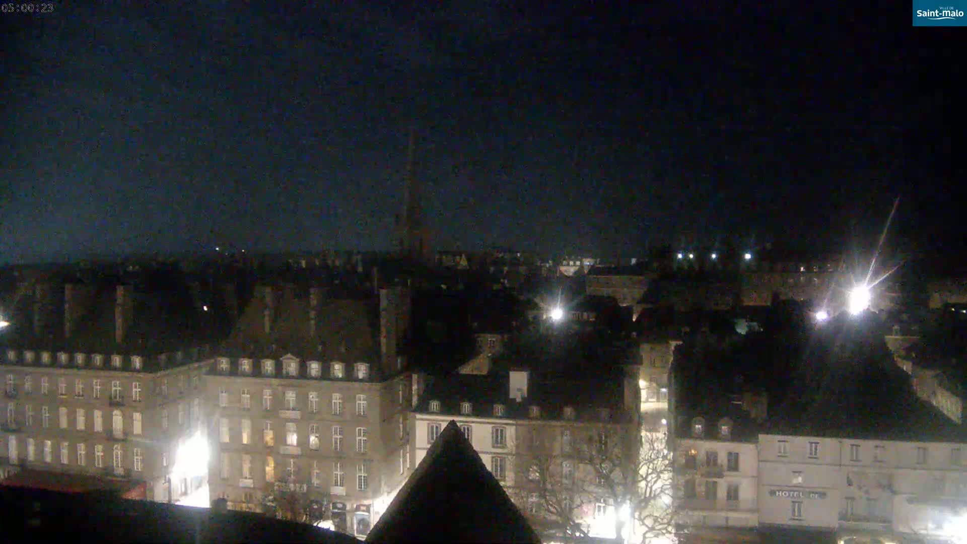 A nighttime, high-angle view of a city with many buildings illuminated by streetlights under a dark sky.