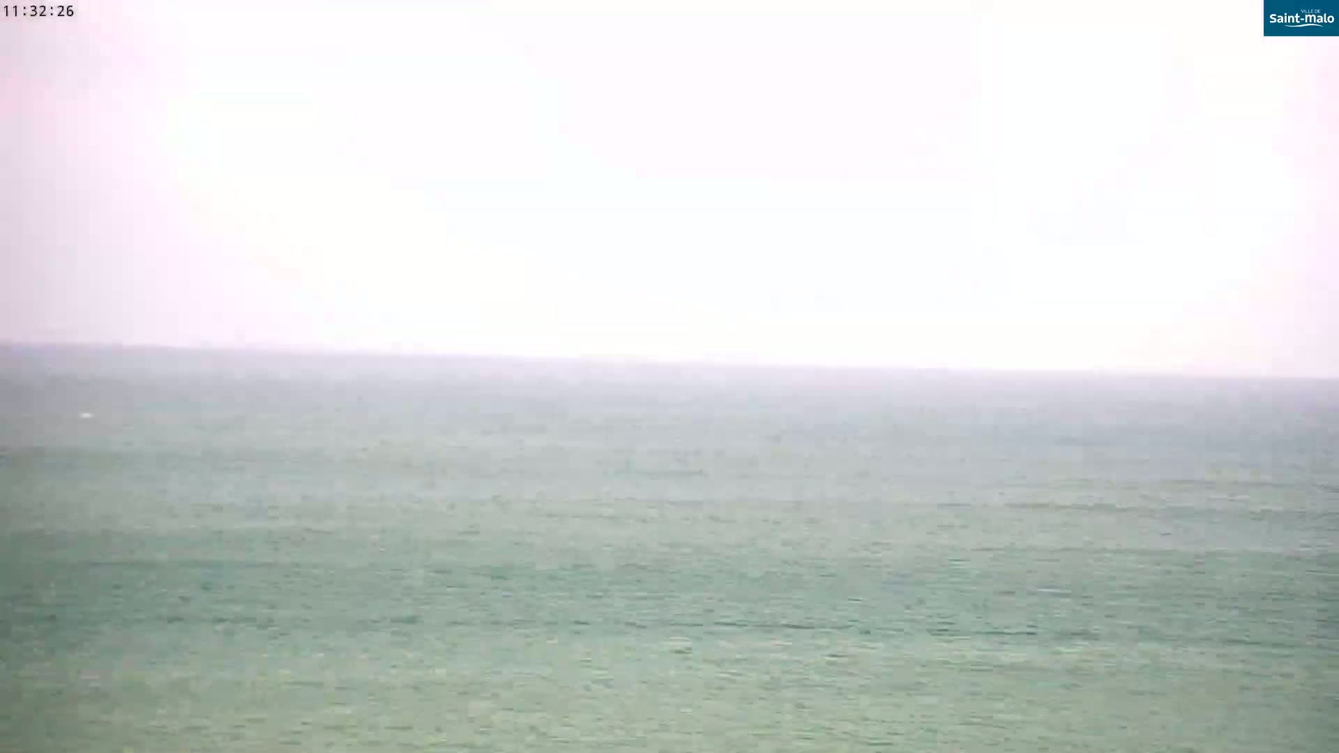 A calm, hazy ocean is visible under a light, overcast sky.