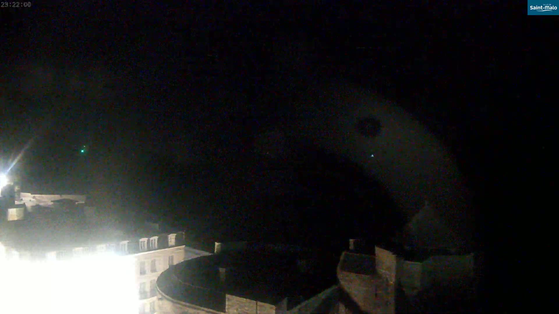 A nighttime, high-angle view shows brightly lit buildings below a dark sky.
