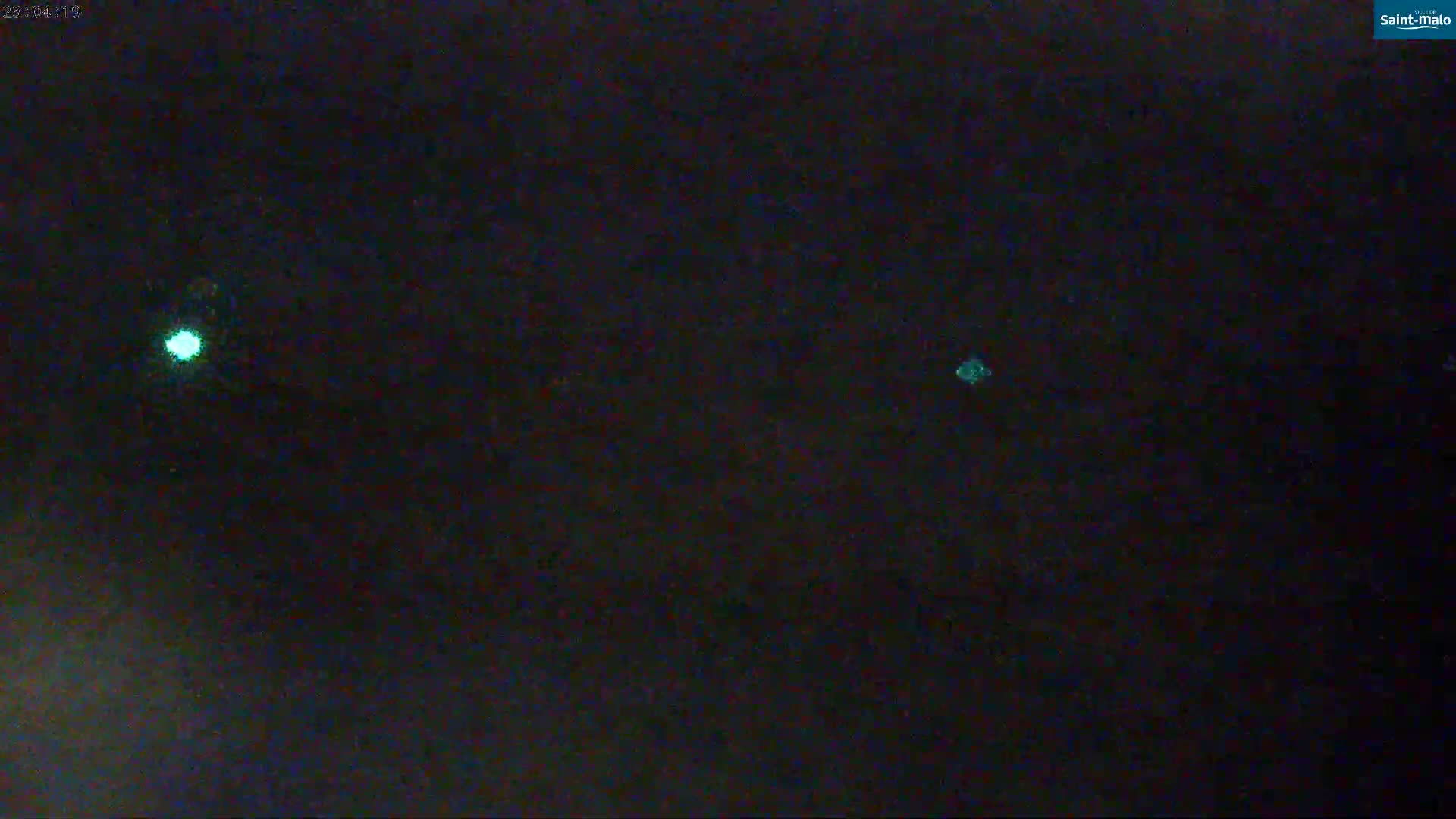 A nighttime, dark sky shows three small, bright, teal-green lights.