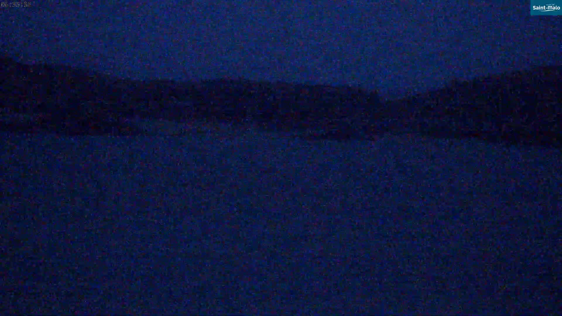 A dark, nighttime view of a body of water with a dark shoreline in the background.