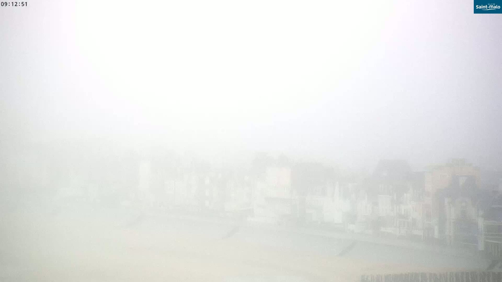 A very foggy view of buildings near a body of water.