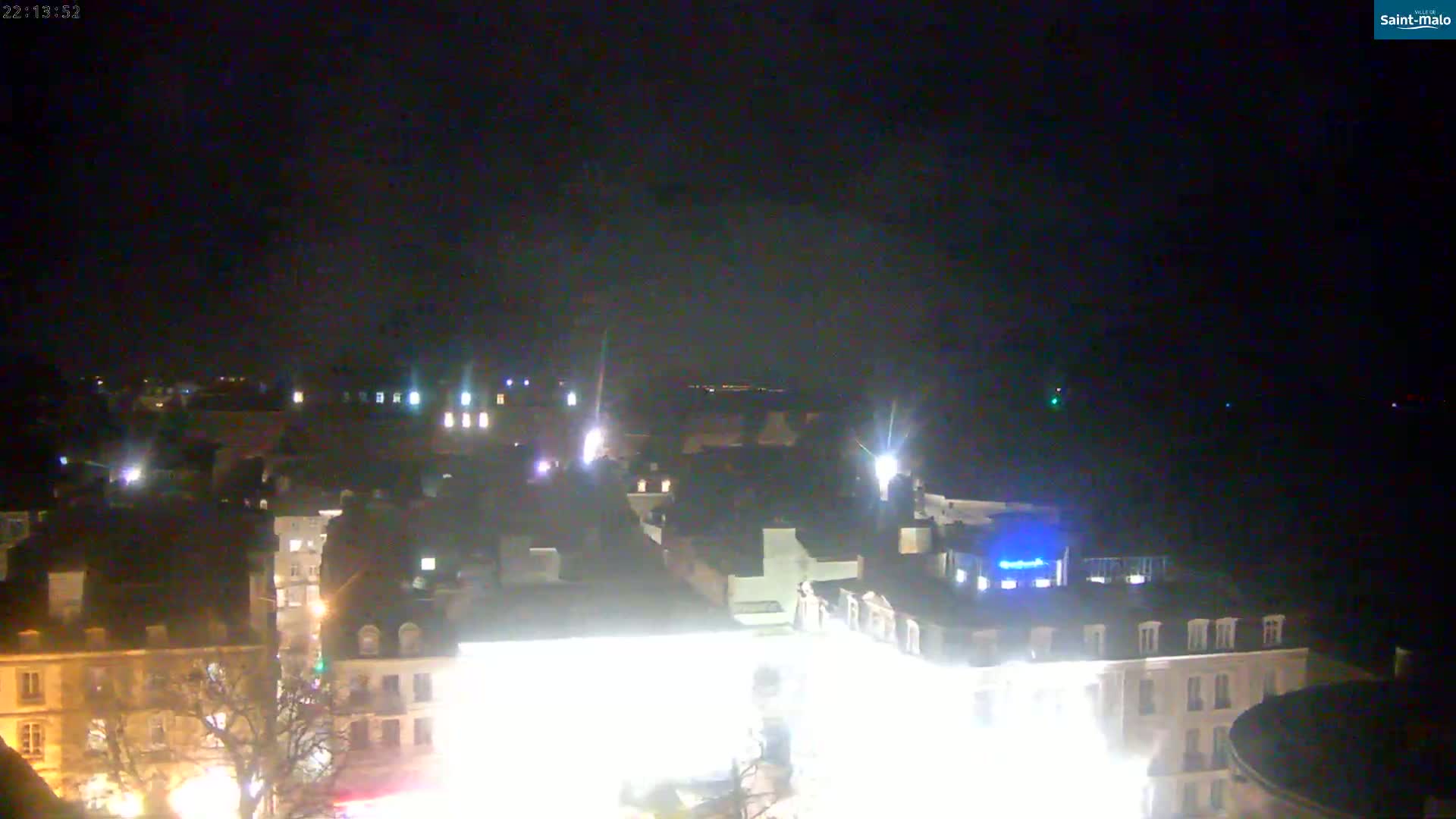 A nighttime, high-angle view of a city illuminated by artificial lights, under a dark, clear sky.