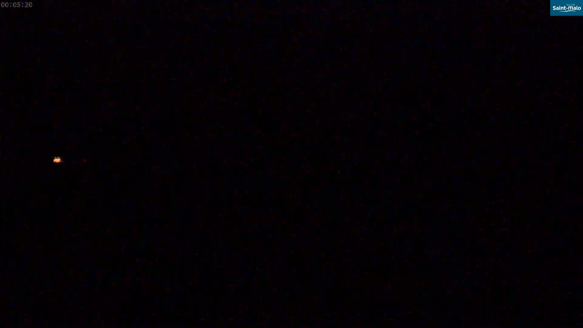 A small, faint orange light is visible in the center-left of a completely dark, nighttime scene.