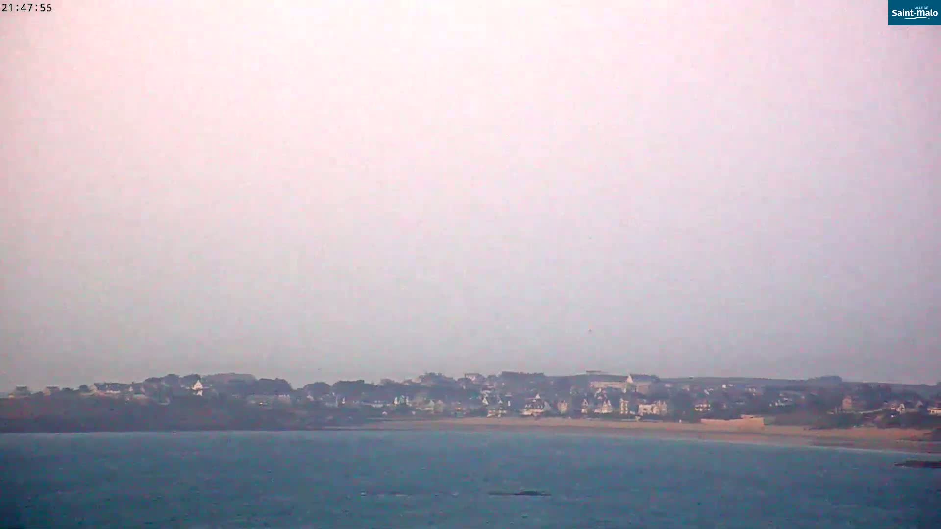 A hazy coastal town is visible across a calm body of water.
